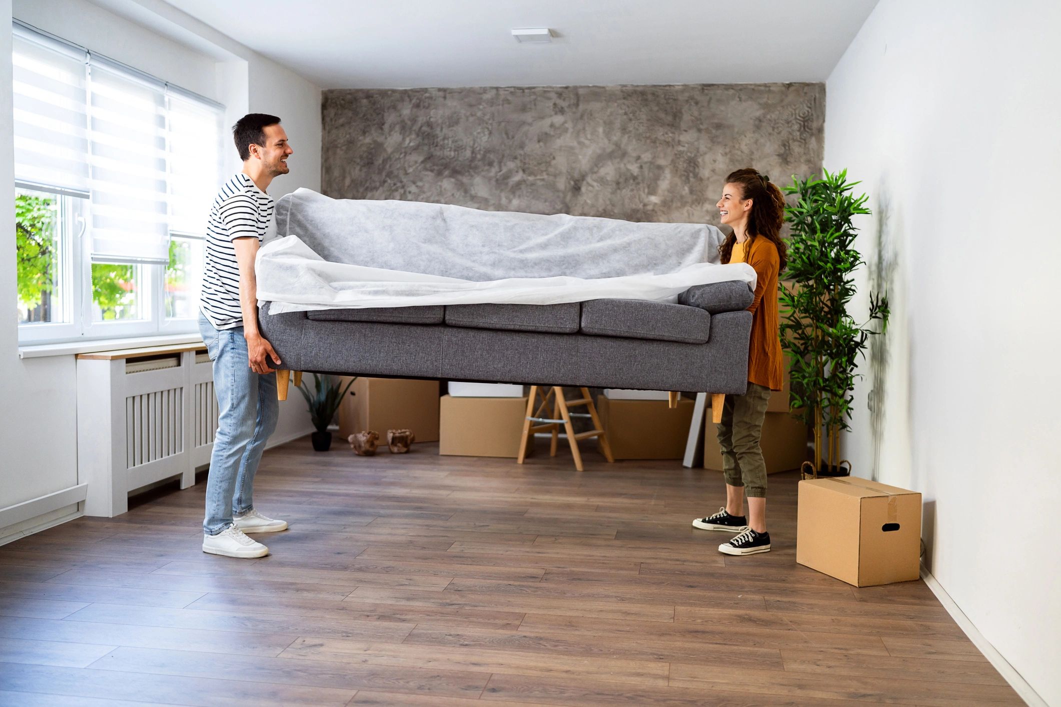 Two people carrying a sofa into a new home